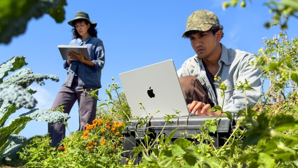 Two people doing outdoor fieldwork with a MacBook Pro with M6