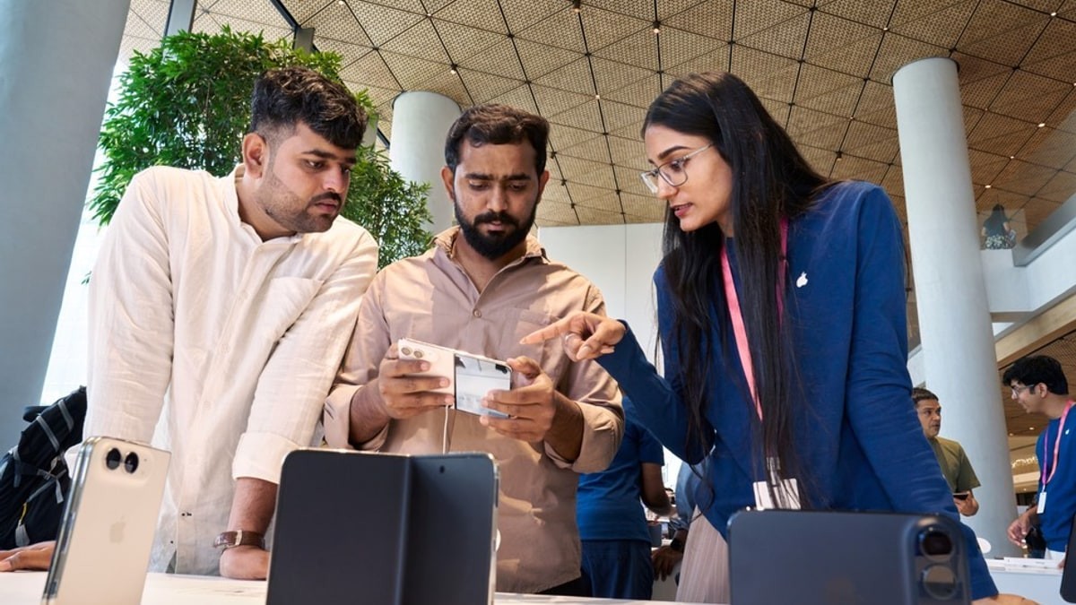 Apple team member and customers examining iPhone Duo at Apple BKC in Mumbai.